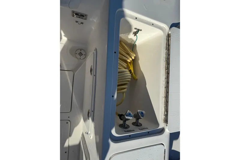 Slide: The Image of 2001 Marlago 35 Cuddy boat storage compartment with coiled yellow hose. - 33