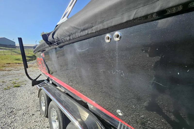 Slide: The Image of 2006 MasterCraft X-80 boat on trailer, black exterior with red accents, covered and parked outdoors. - 11