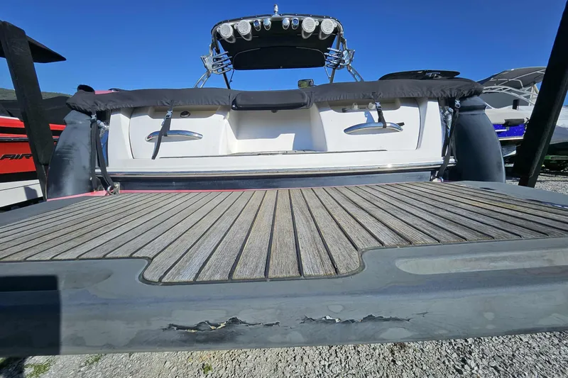 Slide: The Image of 2006 MasterCraft X-80 boat with wooden deck and visible wear, parked outdoors. - 13