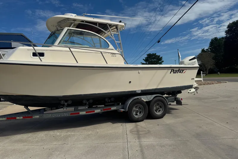Slide: The Image of 2008 Parker 2510 XL Walkaround boat on trailer, parked outdoors under blue sky. - 2