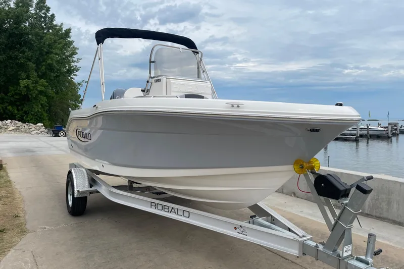Slide: The Image of 2026 Robalo R180 Center Console boat on trailer by the waterfront. - 1