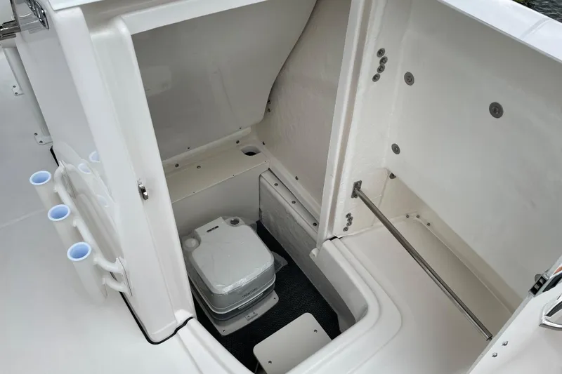 Slide: The Image of 2026 Robalo R180 Center Console boat interior storage compartment with portable toilet. - 12