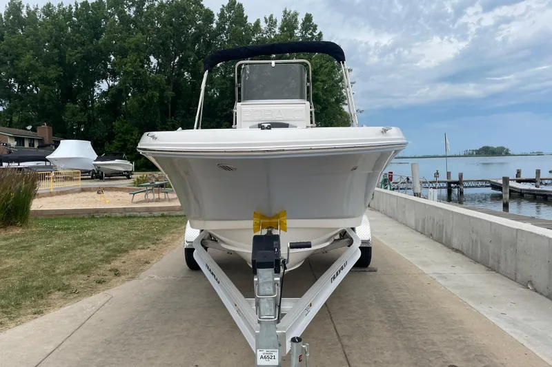 Slide: The Image of 2026 Robalo R180 Center Console boat on trailer by lakeside dock. - 2