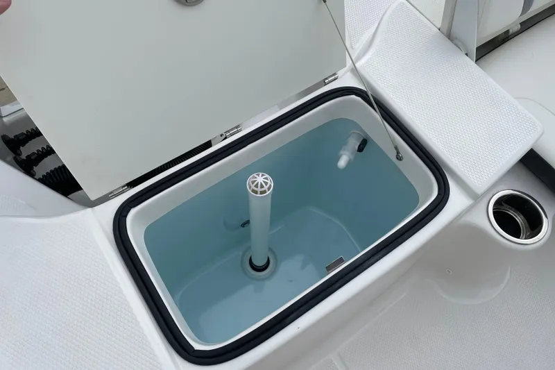 Slide: The Image of 2026 Robalo R180 Center Console livewell with open lid and white interior. - 23