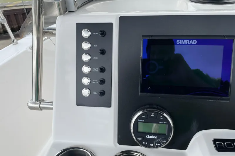 Slide: The Image of 2026 Robalo R180 Center Console dashboard with Simrad display and Clarion audio controls. - 27