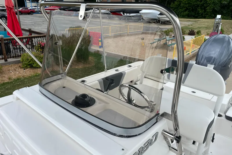 Slide: The Image of 2026 Robalo R180 Center Console boat with steering wheel and windshield, docked outdoors. - 29