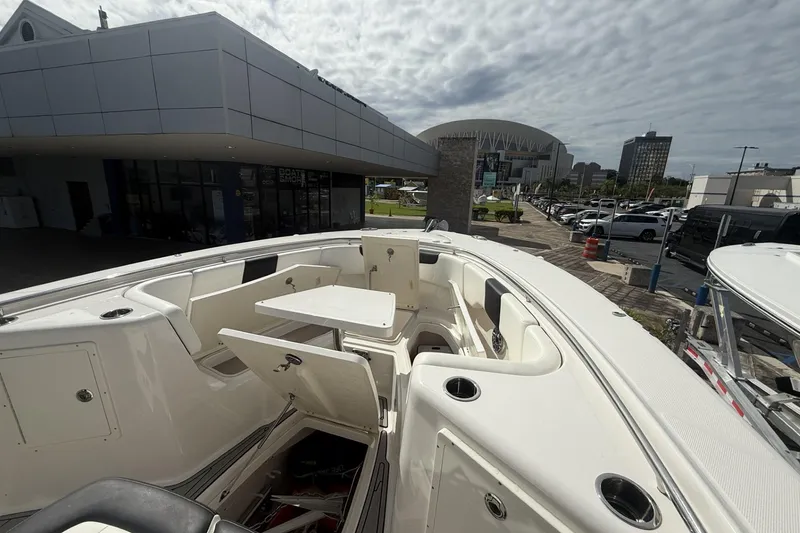 Slide: The Image of 2023 Robalo R302 Center Console boat with seating and table, docked near a modern building. - 4