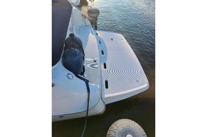 Slide: The Image of 2003 Regal Commodore 3060 boat docked, showing swim platform and water reflection. - 2