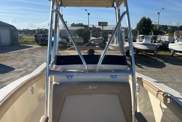 Slide: The Image of 2022 Scout 215 XSF boat with T-top, parked outdoors in a boat dealership. - 17