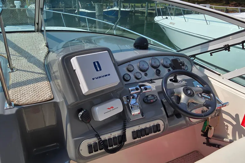 Slide: The Image of 2005 Cruisers Yachts 340 Express helm with steering wheel and navigation controls. - 12