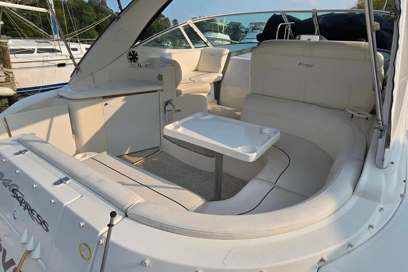 Slide: The Image of 2005 Cruisers Yachts 340 Express interior with white seating and table, docked at marina. - 7