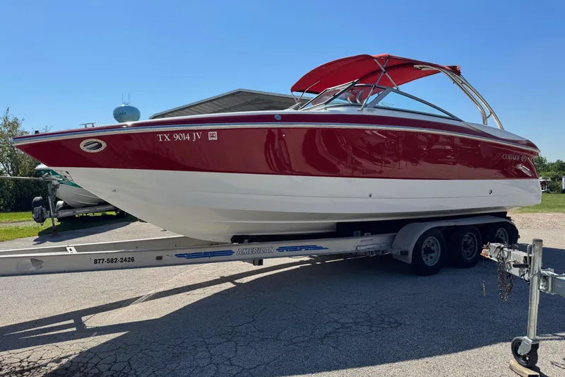 Slide: The Image of 2003 Cobalt 282 boat with red and white exterior on a trailer, sunny day. - 1