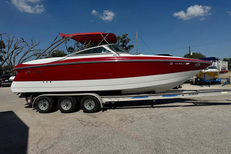 Slide: The Image of 2003 Cobalt 282 boat with red and white exterior on a trailer, parked outdoors. - 2
