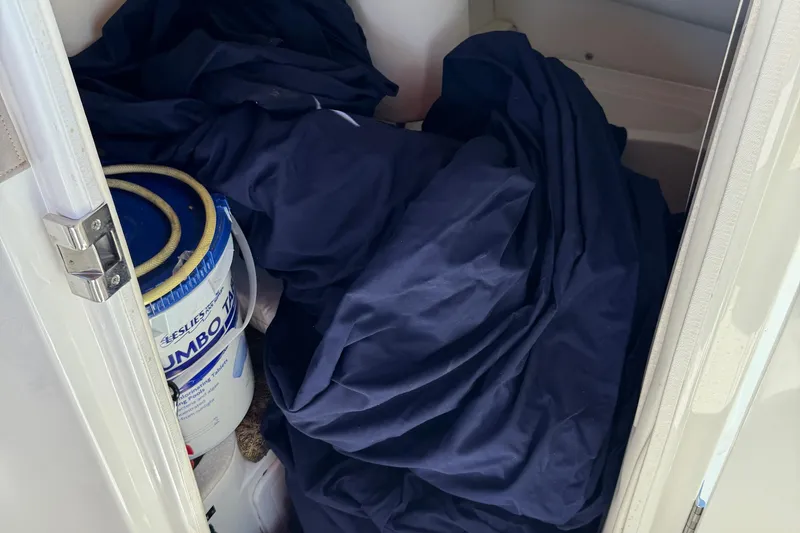 Slide: The Image of Storage compartment in a 2003 Cobalt 282 boat with tarp and bucket. - 34