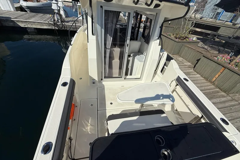 Slide: The Image of 2024 Bayliner Trophy T25 Pilothouse boat interior at dock, featuring seating and table. - 19