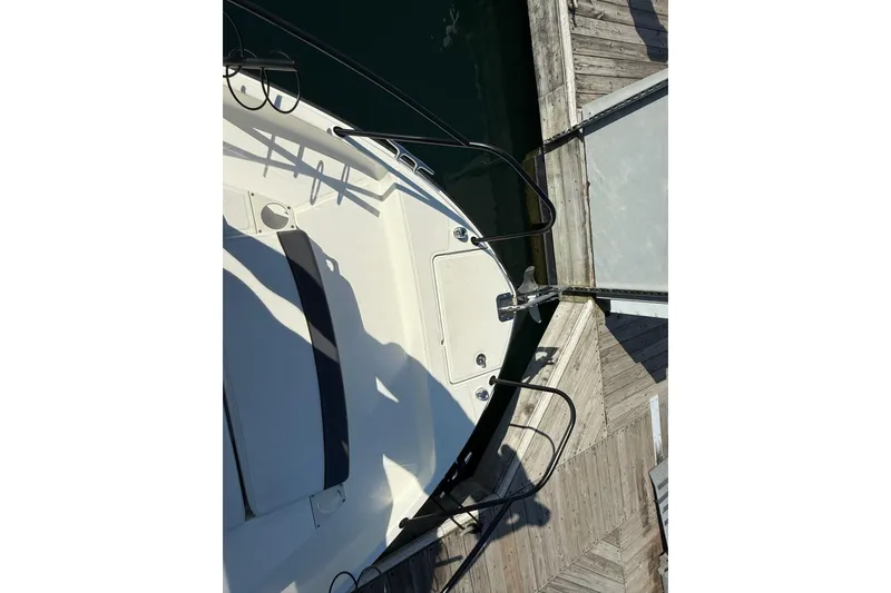 Slide: The Image of 2024 Bayliner Trophy T25 Pilothouse boat docked at a wooden pier. - 23