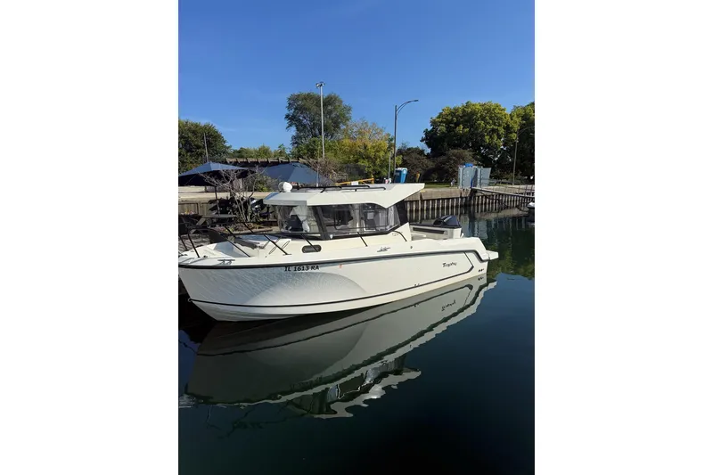 Slide: The Image of 2024 Bayliner Trophy T25 Pilothouse boat docked on calm water, under clear blue sky. - 3
