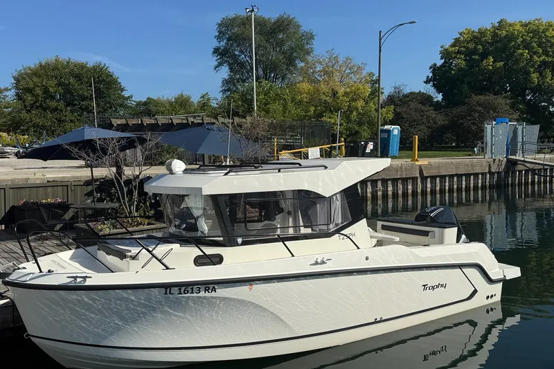 Slide: The Image of 2024 Bayliner Trophy T25 Pilothouse boat docked by a scenic waterfront. - 5