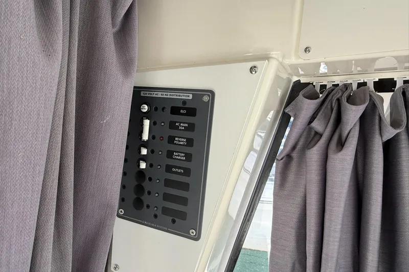 Slide: The Image of 2024 Bayliner Trophy T25 Pilothouse electrical panel with gray curtains. - 50
