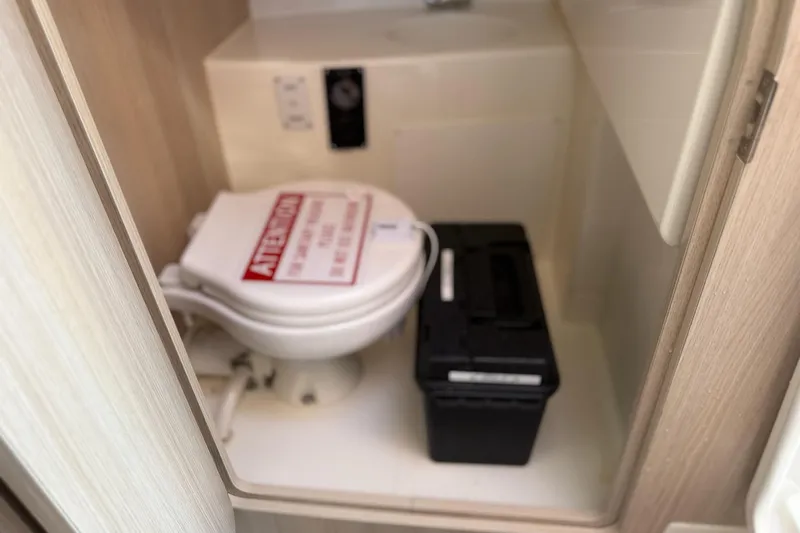 Slide: The Image of 2024 Bayliner Trophy T25 Pilothouse interior with compact marine toilet and storage compartment. - 54