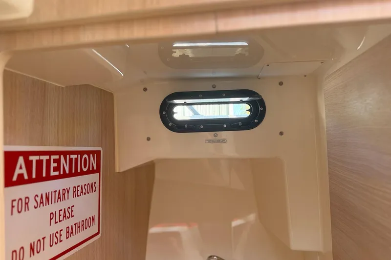 Slide: The Image of Interior of 2024 Bayliner Trophy T25 Pilothouse with a warning sign about bathroom use. - 56