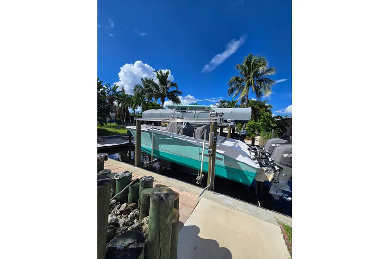 Slide: The Image of 2024 Twin Vee 240 GFX CC boat docked under clear blue sky with palm trees. - 16