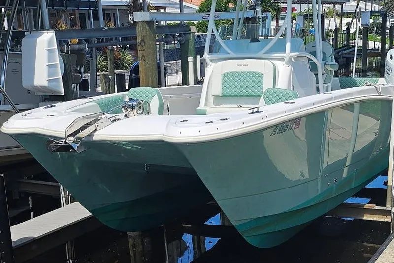 Slide: The Image of 2024 Twin Vee 240 GFX CC boat docked, featuring mint green accents and modern design. - 8