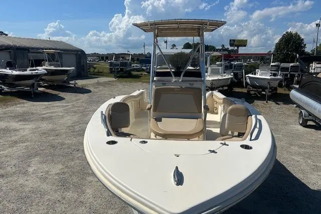 Slide: The Image of 2022 Scout 215 XSF boat with T-top, parked outdoors under a clear sky. - 10