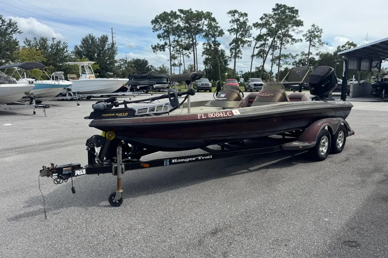 Slide: The Image of 2000 Ranger 520DVX Comanche boat on trailer in parking lot, surrounded by trees and other boats. - 3