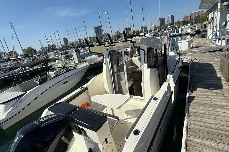 Slide: The Image of 2024 Bayliner Trophy T25 Pilothouse docked at a marina with surrounding boats. - 11