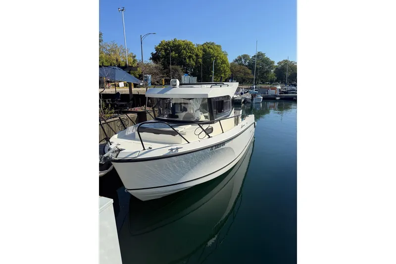 Slide: The Image of 2024 Bayliner Trophy T25 Pilothouse boat docked in a marina under clear blue sky. - 2