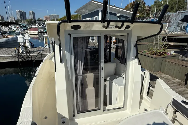 Slide: The Image of 2024 Bayliner Trophy T25 Pilothouse docked at marina, showcasing sliding door and pilothouse interior. - 20