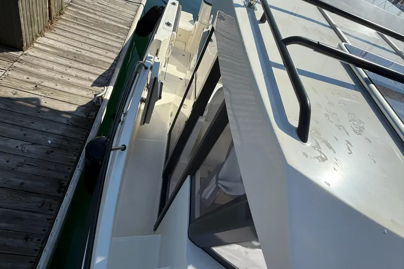 Slide: The Image of 2024 Bayliner Trophy T25 Pilothouse docked, showcasing sleek design and sturdy railings. - 27