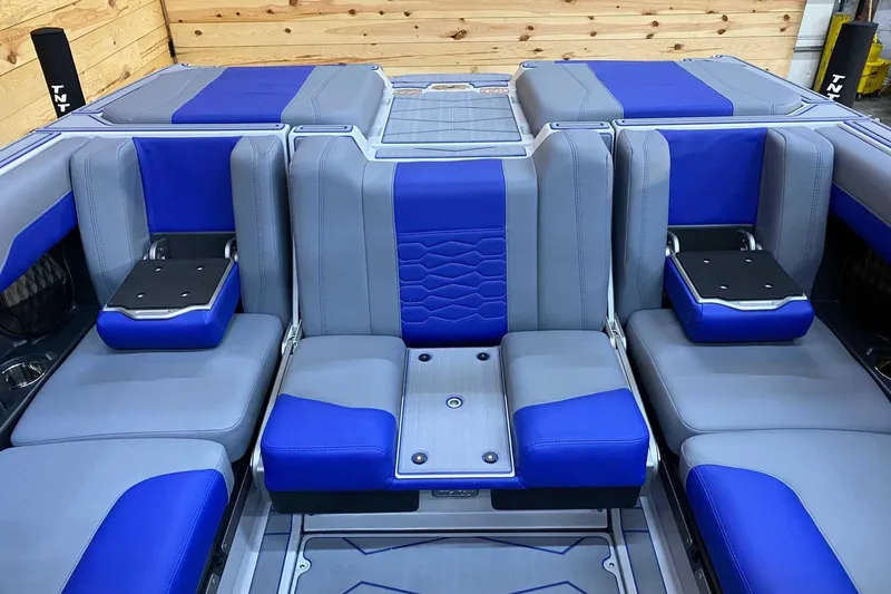 Slide: The Image of 2024 Malibu Wakesetter 23 MXZ interior with blue and gray seating, wooden backdrop. - 8