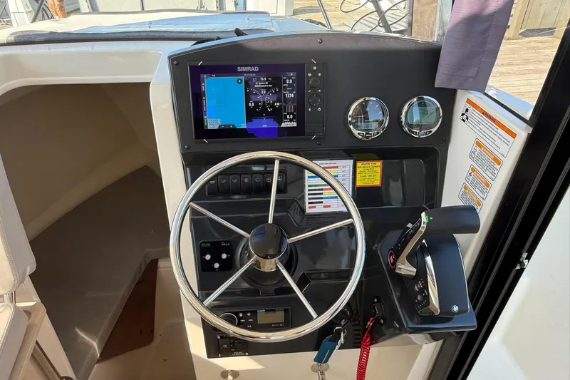 Slide: The Image of 2024 Bayliner Trophy T25 Pilothouse helm with steering wheel, controls, and navigation display. - 36