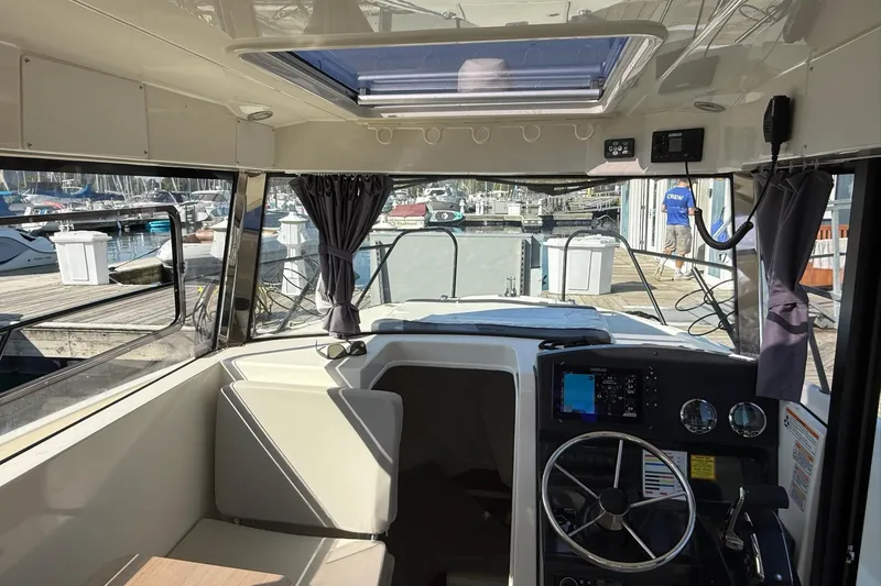 Slide: The Image of 2024 Bayliner Trophy T25 Pilothouse interior with steering wheel and dashboard, docked at marina. - 39