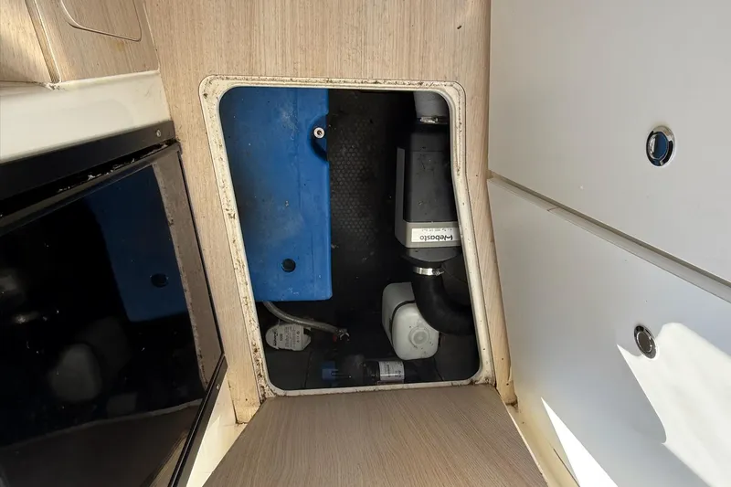 Slide: The Image of 2024 Bayliner Trophy T25 Pilothouse interior compartment with visible equipment and storage. - 49