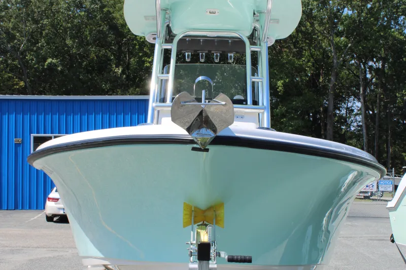 Slide: The Image of 2024 Key West 219 FS boat front view, parked outdoors near a blue building. - 2