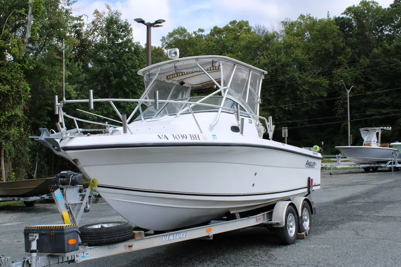 The Image of 2005 Angler 220 WA boat on trailer, parked outdoors with trees in background. - 1