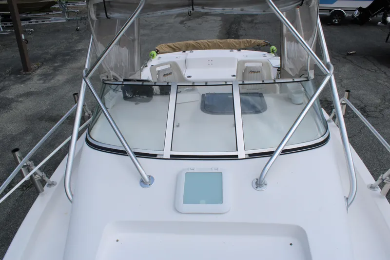 Slide: The Image of 2005 Angler 220 WA boat with windshield and seating, docked on pavement. - 25