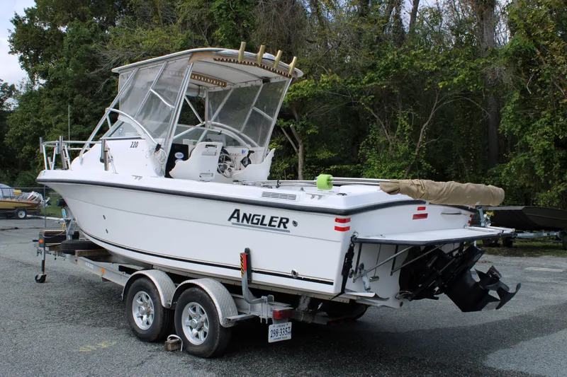 Slide: The Image of 2005 Angler 220 WA boat on trailer, parked outdoors near trees. - 3