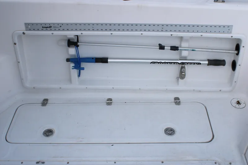Slide: The Image of Storage compartment on 2005 Angler 220 WA boat with fishing tools and measuring ruler. - 31