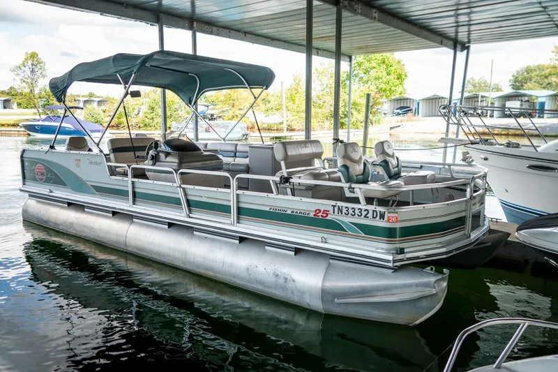 The Image of 2000 Sun Tracker Fishin' Barge 25 pontoon boat docked under a covered marina. - 1
