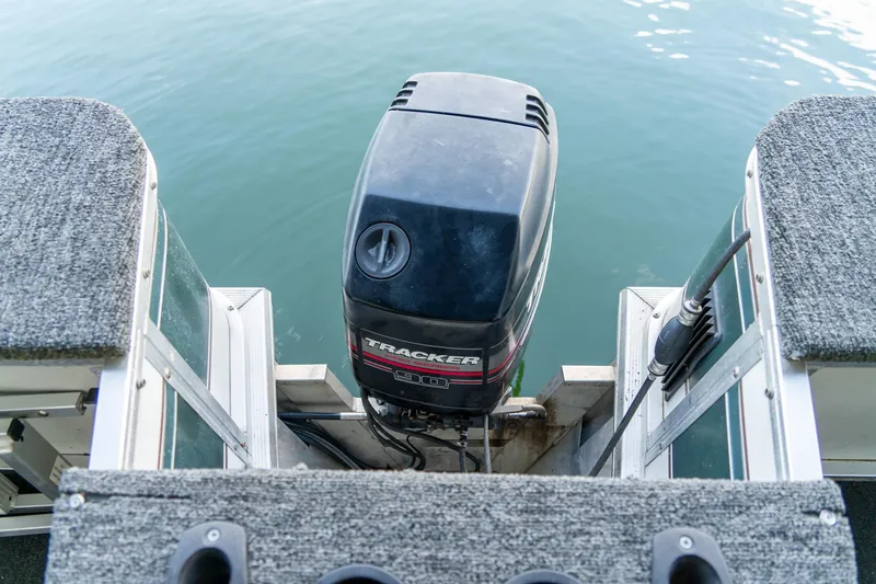 Slide: The Image of Sun Tracker Fishin' Barge 25, 2000 model, with outboard motor on calm water. - 16