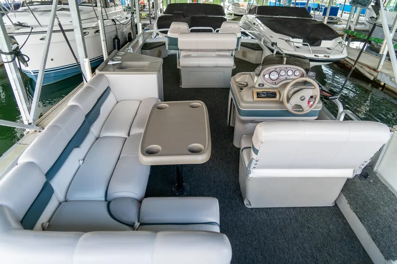 Slide: The Image of 2000 Sun Tracker Fishin' Barge 25 interior with seating, table, and steering console. - 18