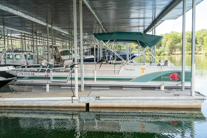 Slide: The Image of 2000 Sun Tracker Fishin' Barge 25 pontoon boat docked under a covered marina. - 3