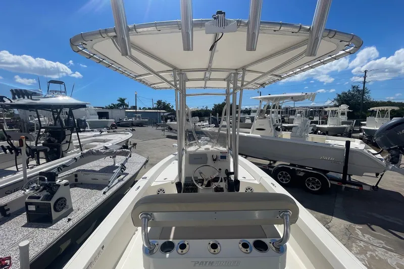 Slide: The Image of 2016 Pathfinder 2200 TRS boat with T-top, parked among other boats under a clear blue sky. - 6