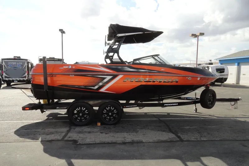 Slide: The Image of 2017 Moomba Craz boat in vibrant orange on a trailer, parked outdoors. - 5