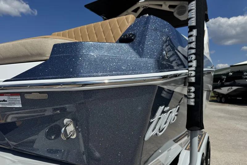 Slide: The Image of 2026 Tigé Z3 boat with sparkling blue finish and tan seating under a clear sky. - 18