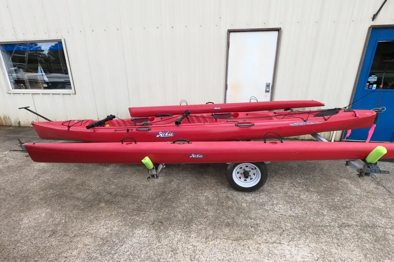 Slide: The Image of Red 2012 Hobie Mirage Tandem Island kayak on trailer, parked outside a building. - 10